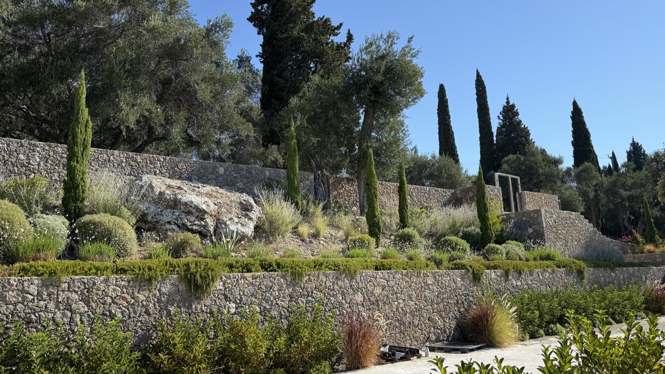 Villa No. 7, Battered honey-stone terraces stepping a steep site beneath a limestone cliff.